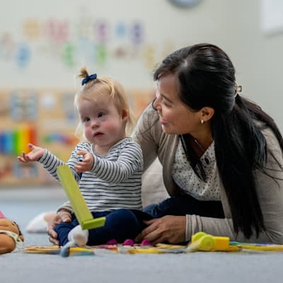 Young child with developmental delays playing with toys in front of pediatric doctor.