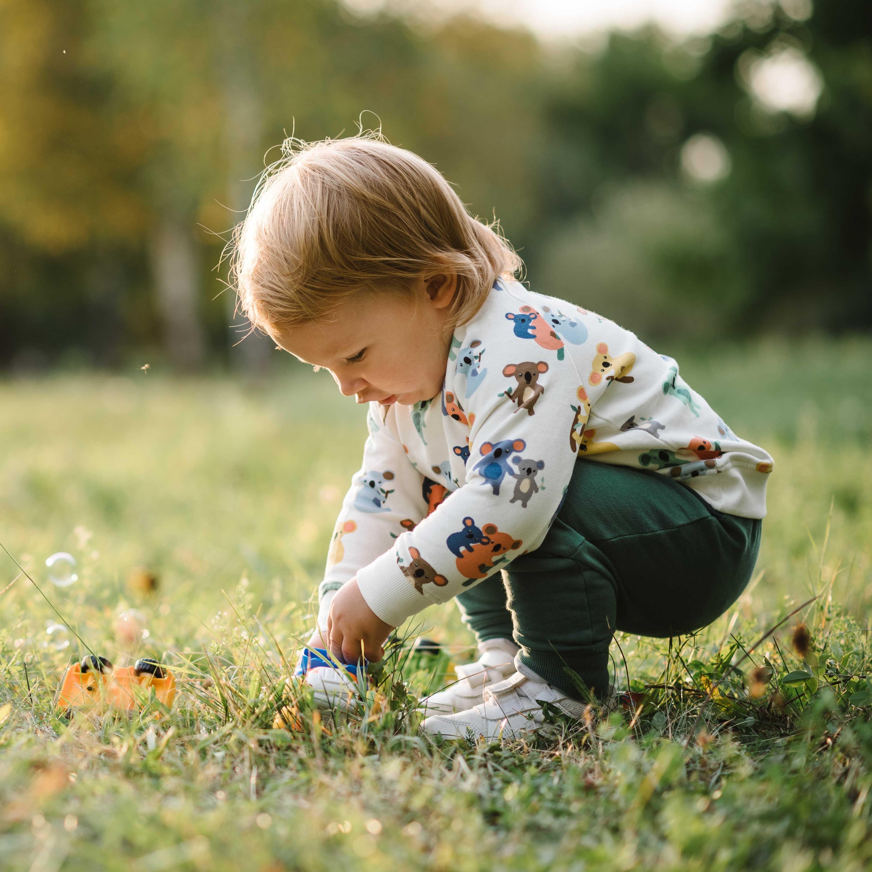 Young child outside playing with bubbles.