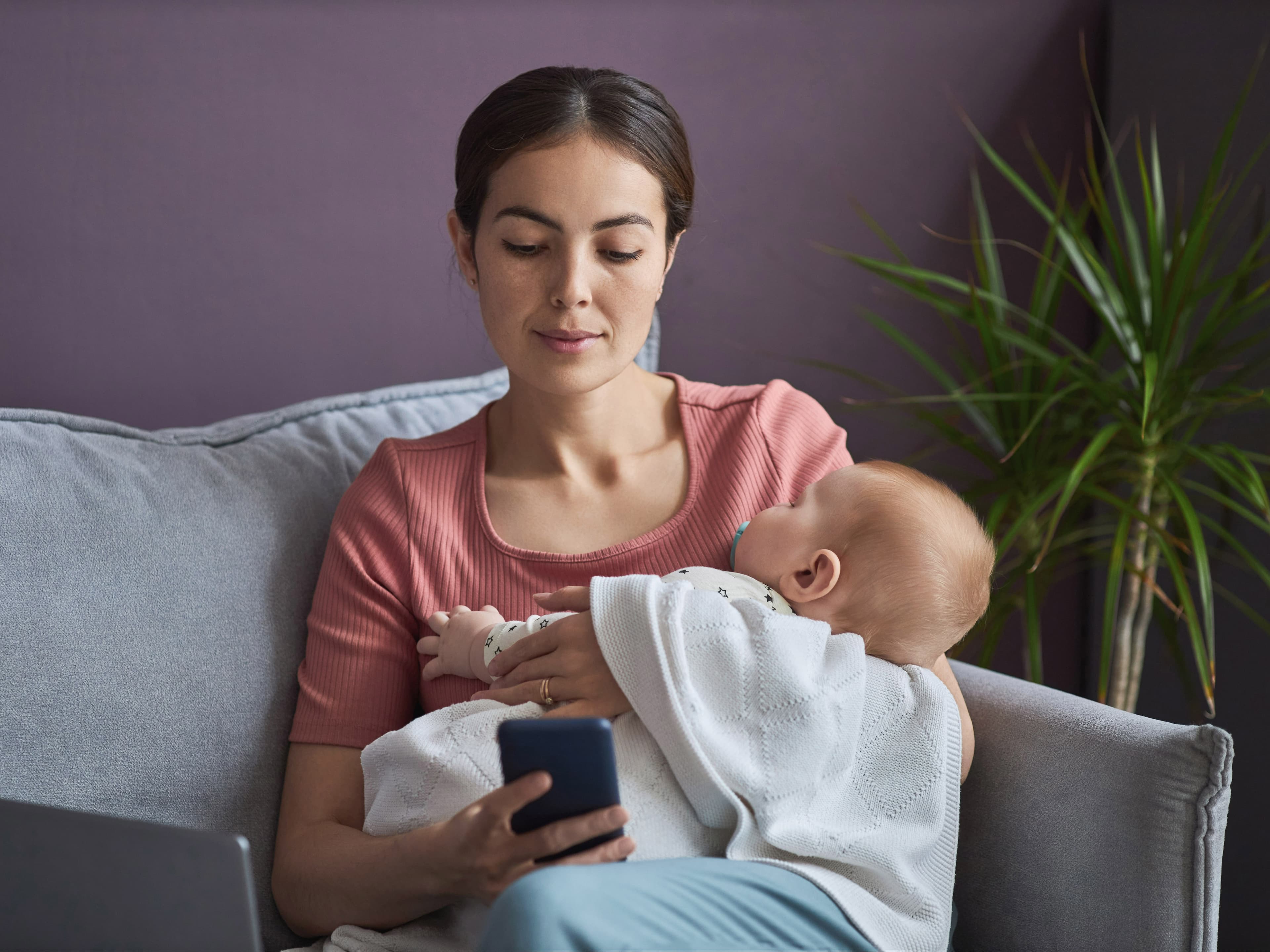 Parent researching while holding child.