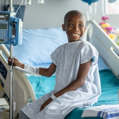 Young child smiling in hospital bed.
