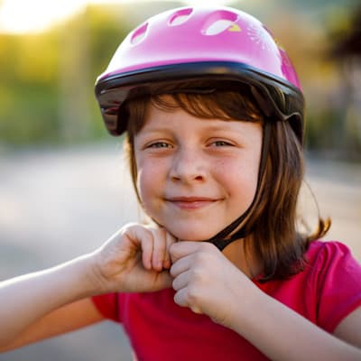 Young girl strapping on her helmet.