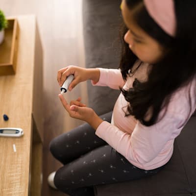 Child checking blood sugar with finger poke.