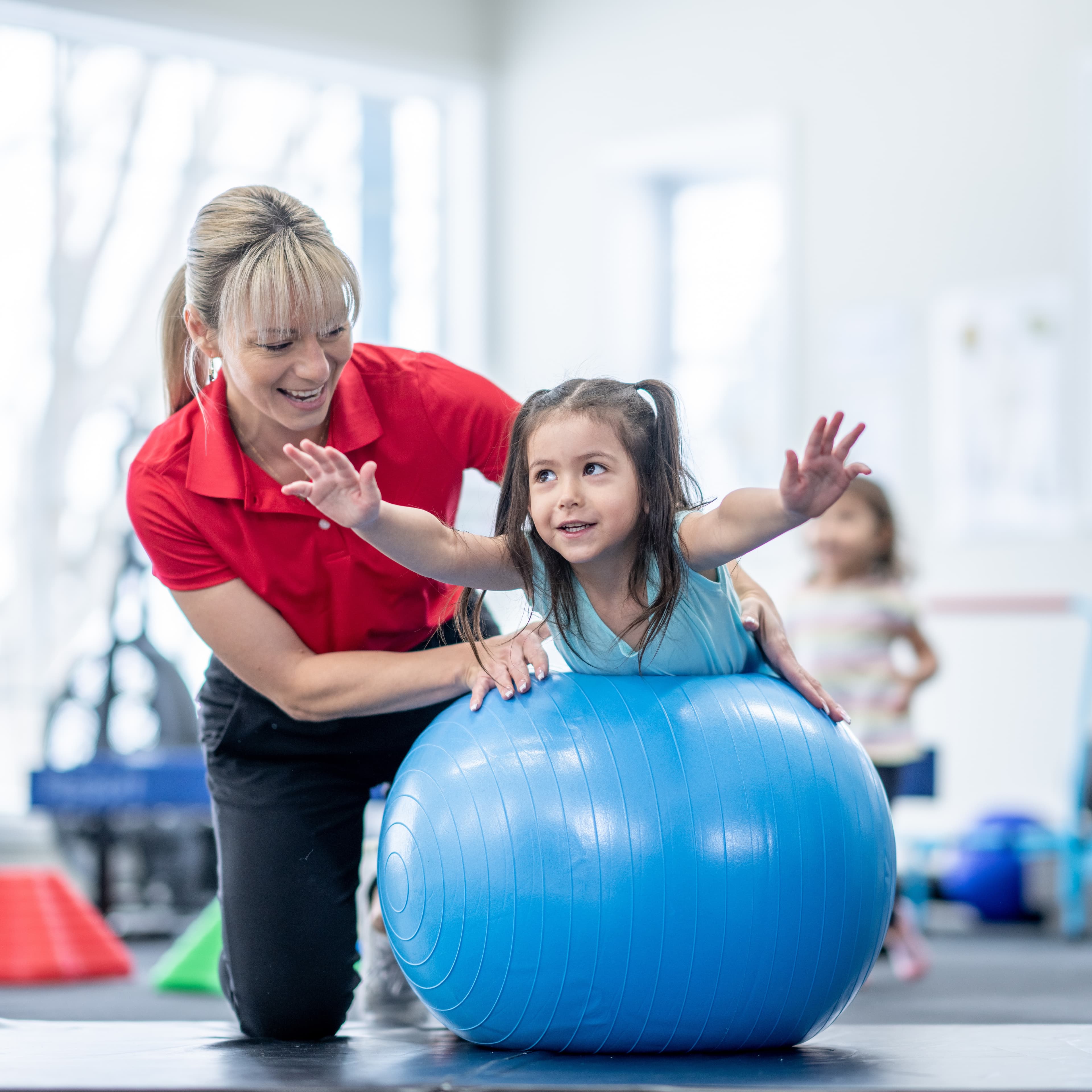 Therapist working with young girl on exercise ball.